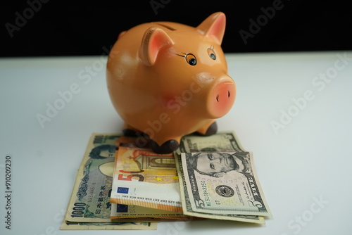 Wallpaper Mural Horizontal photo of a piggy bank on several dollar, euro and yen bills as a currency saving concept Torontodigital.ca