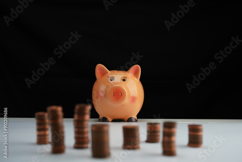 Stacked coins of different currencies in front of a piggy bank focused on the background as a concept of saving for home purchase