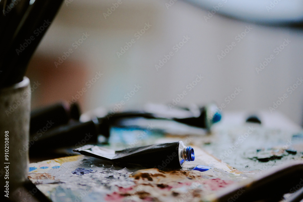 Closeup of opened acrylic or oil paint tubes lying on palettes on table at artists workplace Closeup of opened acrylic or oil paint tubes lying on palettes on table at artists workplace