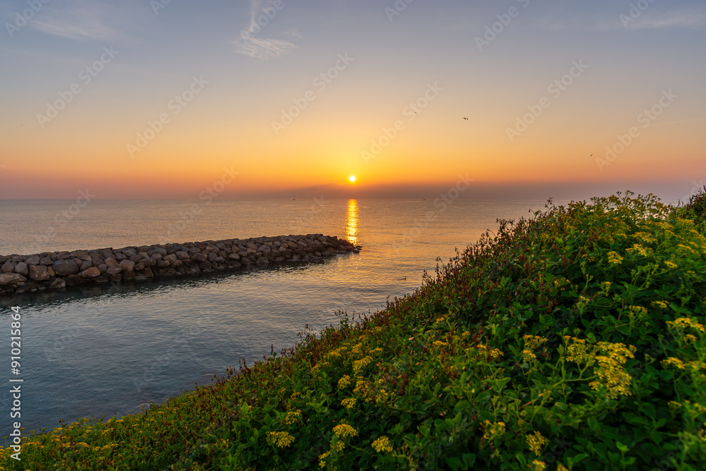 Fototapeta premium Amanecer idílico en la costa rocosa, con olas suaves acariciando la orilla.