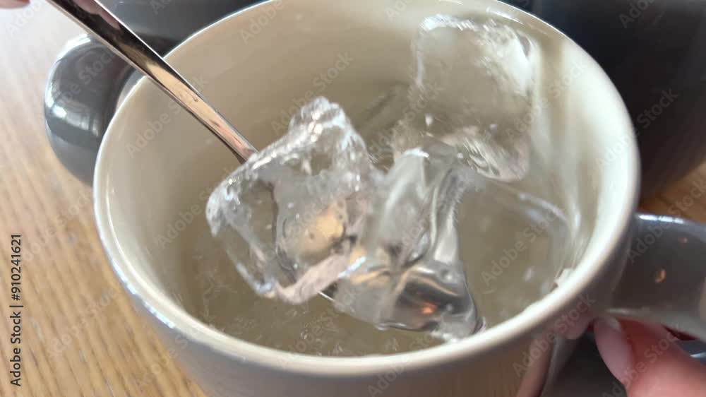 Ice in a cup spoon water glass falling ice cube. slow motion falls ice in cold mineral water. soda water with bubbles on white background. glass water close up. summer drink with ice. fizzy drink. bar Ice in a cup spoon water glass falling ice cube. slow motion falls ice in cold mineral water. soda water with bubbles on white background. glass water close up. summer drink with ice. fizzy drink. bar