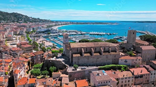 Aerial view Hilltop Gothic-style stone church with city views in Cannes. Aerial view of Cannes Port on the French Riviera, Cote d'Azur with ships and boats. photo