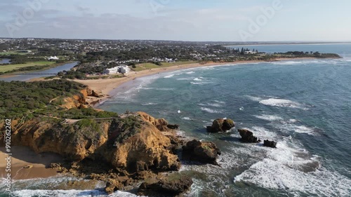 Drone flying over the ocean and its limestone cliffs with sandy beachline and city in the background photo