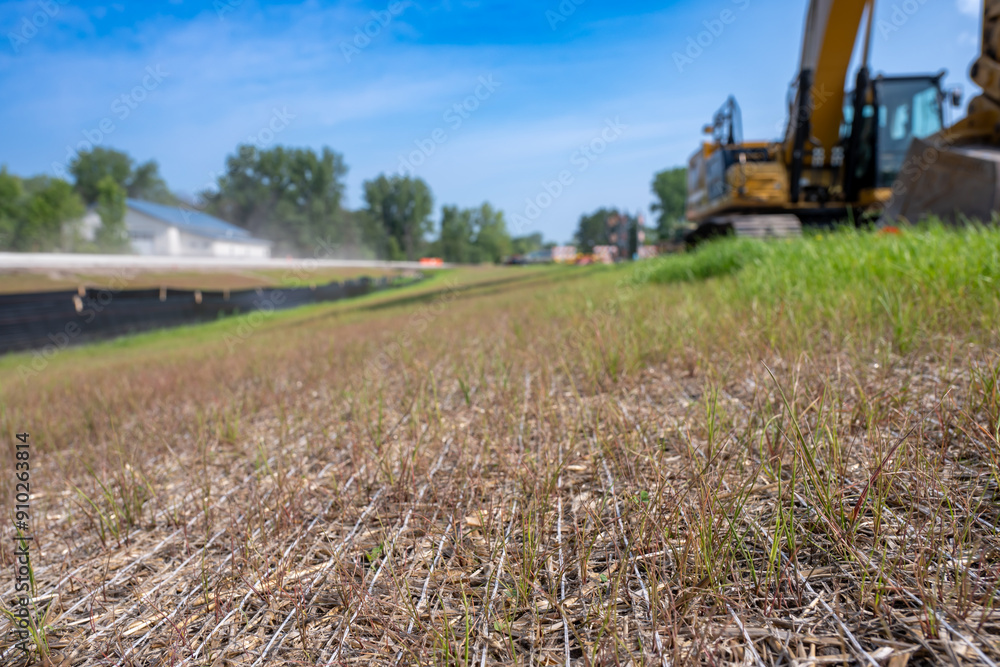 Woven straw mat used for stormwater erosion control with grass growing through 