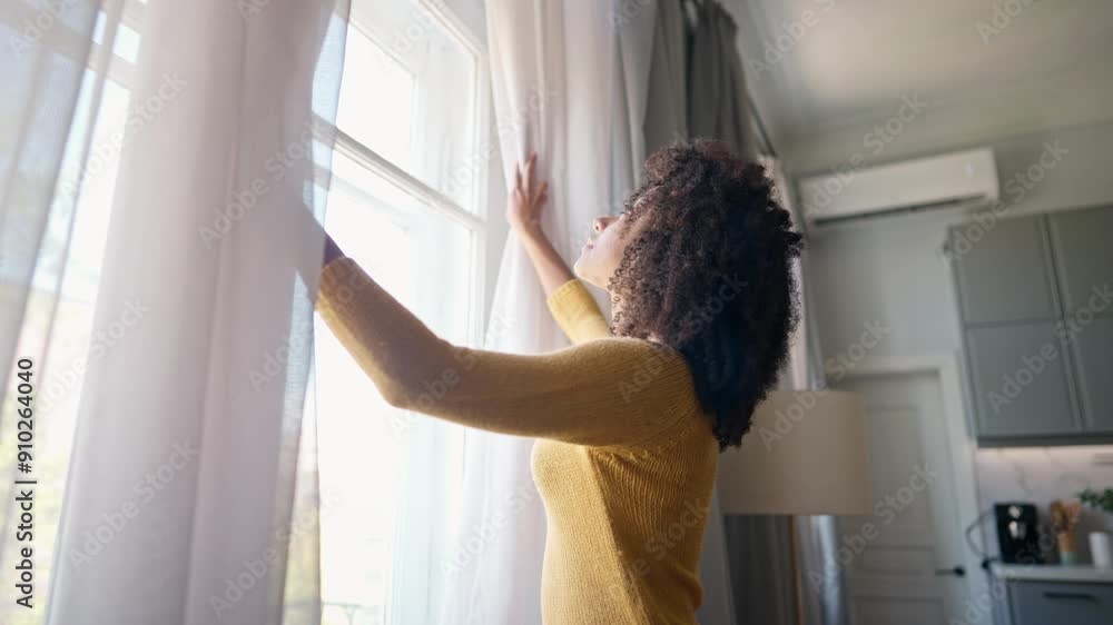 African American woman walking up to window and opening curtains in different sides. Curly female looking outdoor on street. Happily smiling while checking weather outside window. Peaceful day at home African American woman walking up to window and opening curtains in different sides. Curly female looking outdoor on street. Happily smiling while checking weather outside window. Peaceful day at home