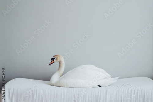 A serene and elegant image of a majestic white swan resting calmly on a smooth white fabric background, embodying purity, grace, and tranquility. photo