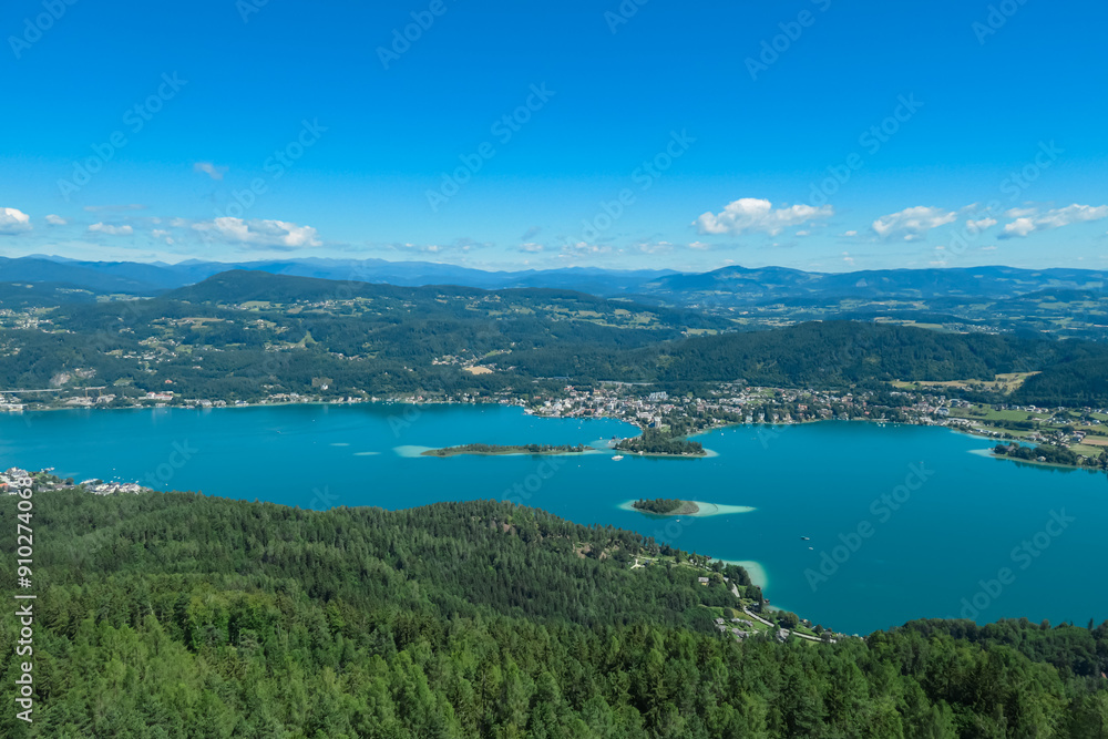 Aerial panoramic view of Lake Wörthersee seen from Pyramindenkogel in Carinthia, Austria. Serene turquoise waters, lush green forests and rolling hills of Austrian Alps. Charming lakeside village Aerial panoramic view of Lake Wörthersee seen from Pyramindenkogel in Carinthia, Austria. Serene turquoise waters, lush green forests and rolling hills of Austrian Alps. Charming lakeside village
