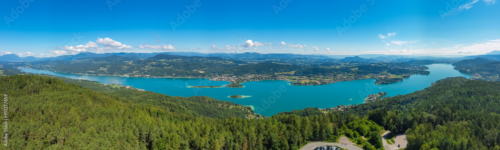 Aerial panoramic view of Lake Wörthersee seen from Pyramindenkogel in Carinthia, Austria. Serene turquoise waters, lush green forests and rolling hills of Austrian Alps. Charming lakeside village Aerial panoramic view of Lake Wörthersee seen from Pyramindenkogel in Carinthia, Austria. Serene turquoise waters, lush green forests and rolling hills of Austrian Alps. Charming lakeside village