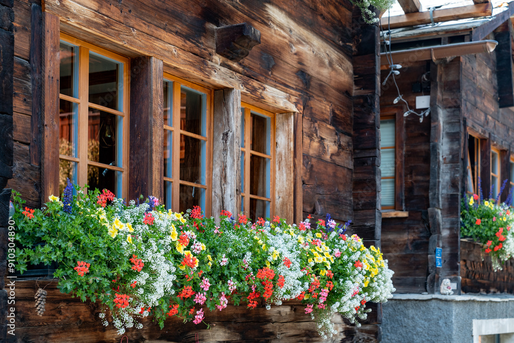 Picturesque chalet window with red flowers in flower box in Zermatt, Switzerland, during summertime Picturesque chalet window with red flowers in flower box in Zermatt, Switzerland, during summertime