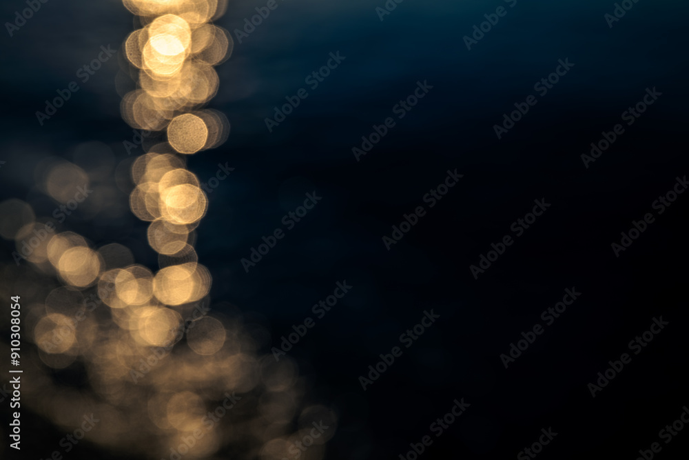 Fototapeta premium blurred background, sunset or sunrise on the sea, a path of light on the water on dark sea background, highlights and bokeh in blur for overlay
