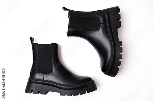 Black leather women classic boots on plain white background. Top view flat lay. Autumn spring winter fashion boots, women's shoes, footwear with thick soles. Fashion and style photo