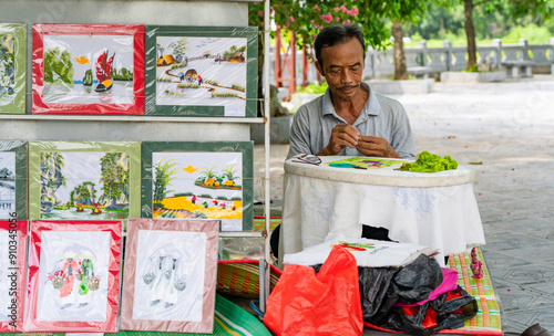 Elderly man creates traditional Vietnamese embroidery photo