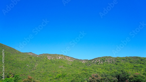 Panoramic view of green hills under a clear blue sky, capturing the vastness and tranquility of nature