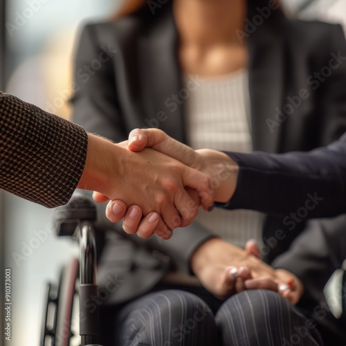 Close up of a handshake in a corporate business environment, woman in a suit sitting in a wheelchair shaking hands in a successful job interview or meetin photo