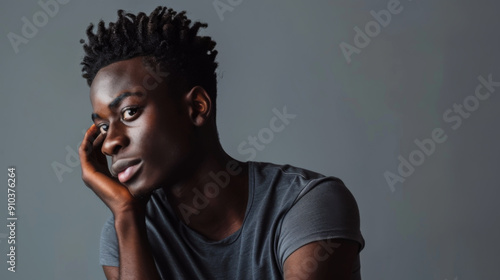 Portrait of a young African American man against a dark background. Handsome man posing indoors. Style and fashion concept.