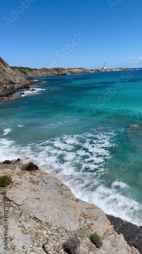 Panoramic view of the idyllic cove of Presili on a sunny day. The Mediterranean Sea displays crystal-clear turquoise and blue hues, contrasting with the golden sand of the beach. Menorca, Spain photo