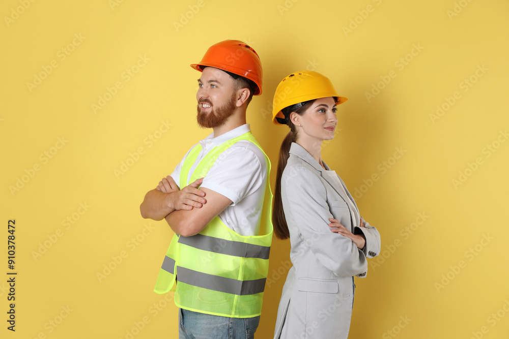 Engineers in hard hats on yellow background Engineers in hard hats on yellow background