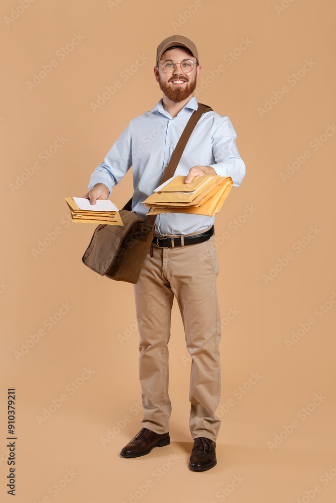 Happy young postman with leather bag delivering letters on brown background Happy young postman with leather bag delivering letters on brown background