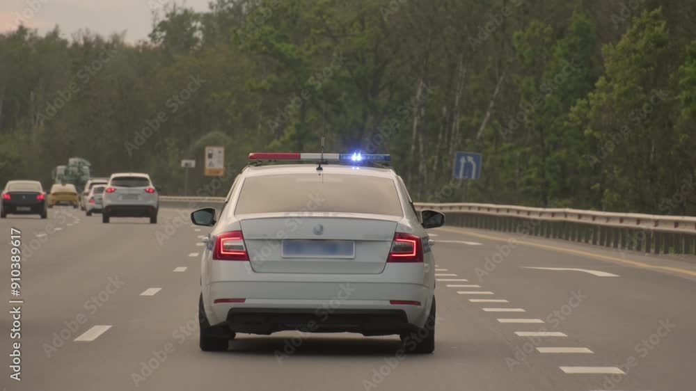 Police patrol car with flashing light drives along highway.