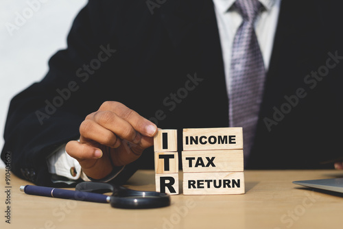 Businessman holding wooden cube word  ITR Income tax return word on wooden cube photo