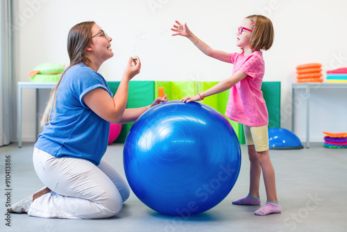 Child with physical disability in bilateral coordination physiotherapy. Child living with cerebral palsy exercising with her therapist during physiotherapy.