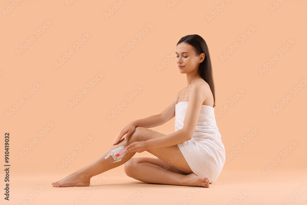 Beautiful woman shaving leg on beige background Beautiful woman shaving leg on beige background