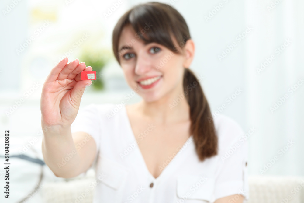 Woman holding SIM card at home, selective focus Woman holding SIM card at home, selective focus