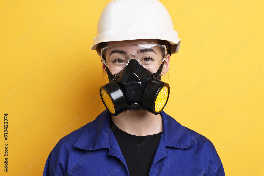 Worker in respirator, protective glasses and helmet on orange background Worker in respirator, protective glasses and helmet on orange background
