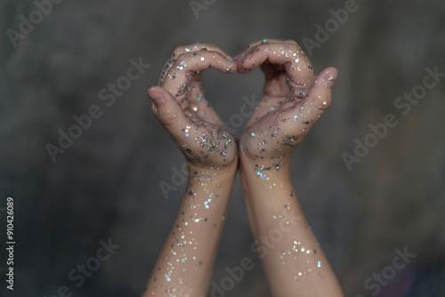 Selective focus on heart-shaped hands. Hands with sequins. The concept of the holiday