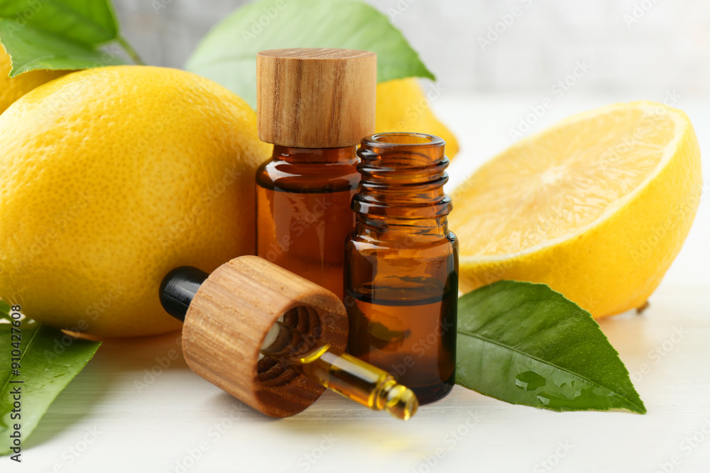 Essential oils in bottles, dropper, lemons and green leaves on white table, closeup Essential oils in bottles, dropper, lemons and green leaves on white table, closeup