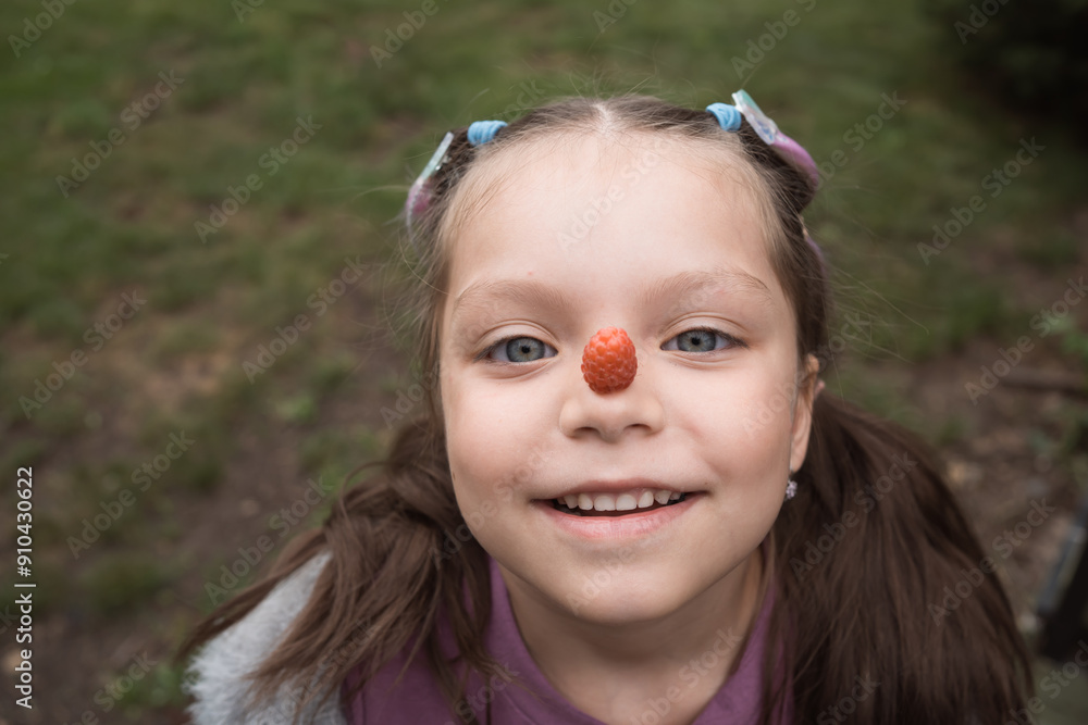 little girl holding berry on nose little girl holding berry on nose