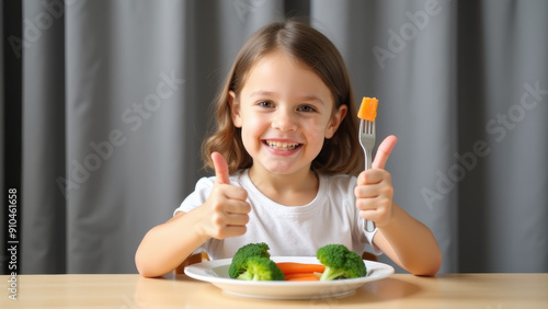 A cheerful young girl with a bright smile gives a thumbs up while eating a plate of healthy vegetables, including carrots and broccoli, promoting nutritious eating.