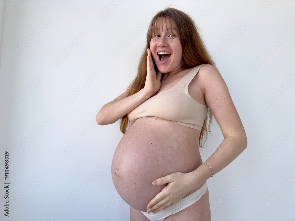 Happy young pregnant woman is stroking her big belly on white background Happy young pregnant woman is stroking her big belly on white background
