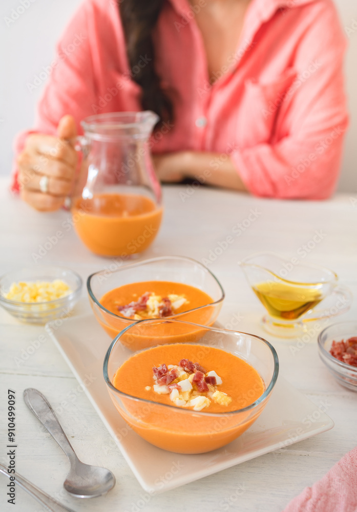 A woman enjoys a meal of salmorejo topped with jamón and boiled egg, embodying Spanish culinary tradition. A woman enjoys a meal of salmorejo topped with jamón and boiled egg, embodying Spanish culinary tradition.