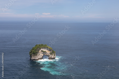 Row of empty deck chairs in cloudy weather on the Atuh beach on the island of Nusa Penida. Sandy beach, green islands,  sea surf and tropical nature around photo