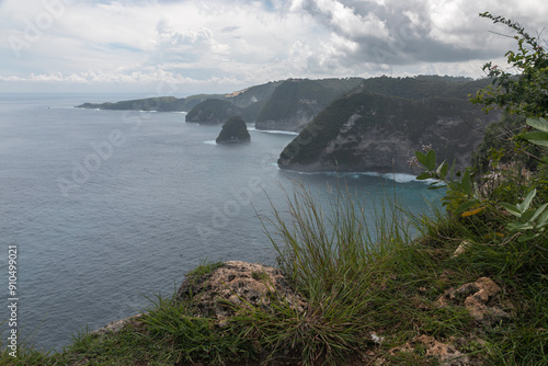 Glued panorama of Amazing landscape of the Banah cliff close to Kelingking Beach in Nusa Penida Island, Bali, Indonesia. Turquoise sea bay with foam surf surrounded by slope green tropical cliffs photo