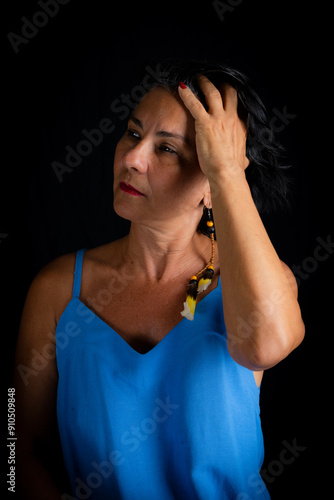 Beautiful mature woman with short black hair in blue dress posing for photo.