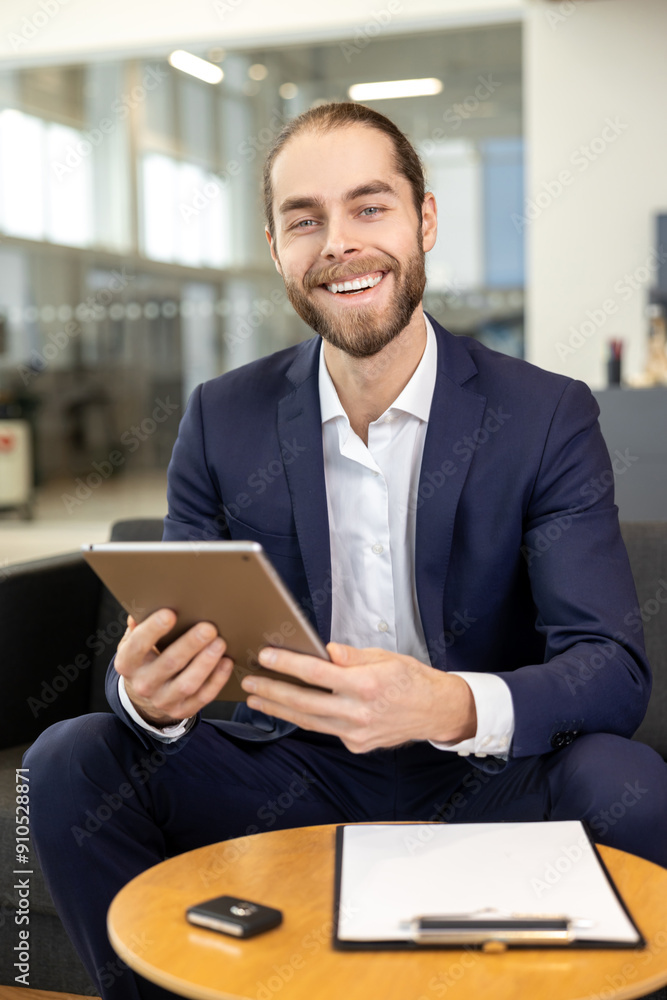 Handsome man working on digital tablet in car showroom Handsome man working on digital tablet in car showroom