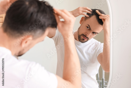 Handsome man combing hair n...