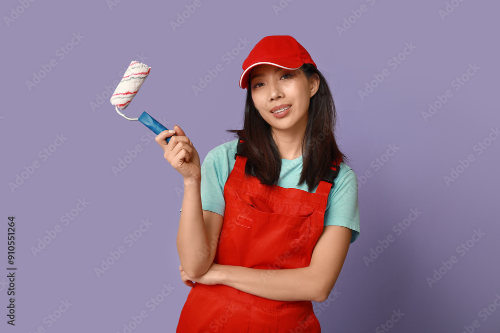 Female Asian painter with roller on purple background
