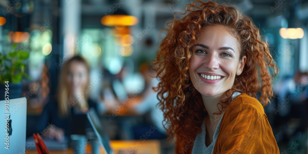 Portrait of a cheerful woman with curly red hair, sitting in a modern office environment, surrounded by colleagues. Portrait of a cheerful woman with curly red hair, sitting in a modern office environment, surrounded by colleagues.