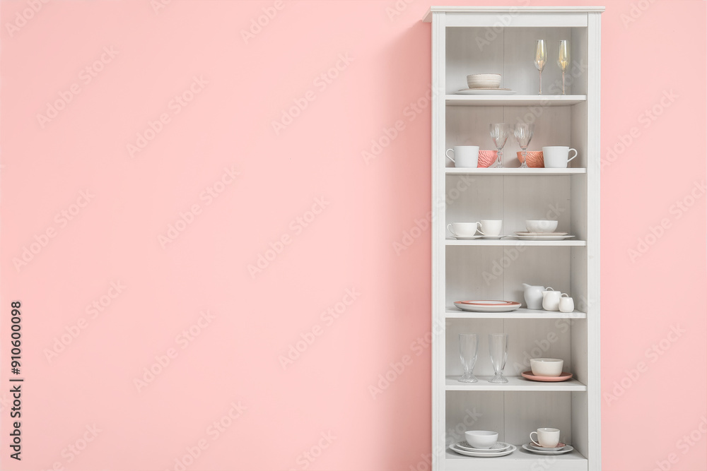 Modern shelving unit with dishes near pink wall in kitchen Modern shelving unit with dishes near pink wall in kitchen