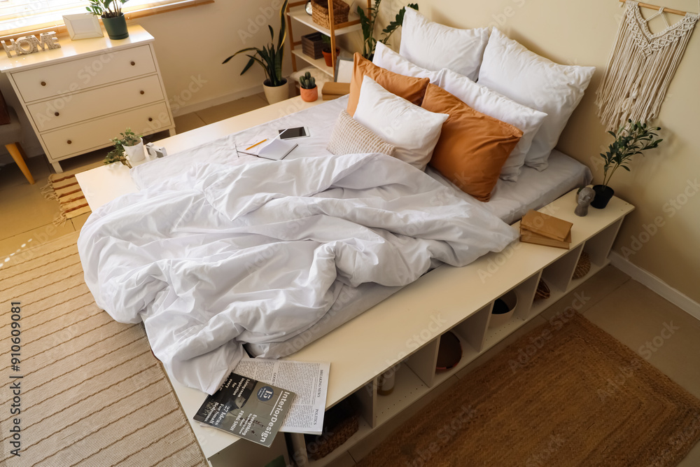 Cozy bed with crumpled linen and chest of drawers in interior of bedroom Cozy bed with crumpled linen and chest of drawers in interior of bedroom