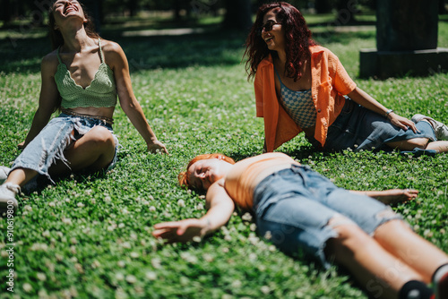 Three young adults enjoying a sunny day in the park, relaxing and laughing on green grass. Capturing relaxation and friendship.