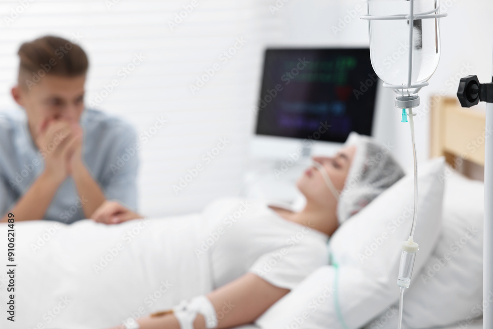 Coma patient. Sad young man near his unconscious wife in hospital, selective focus Coma patient. Sad young man near his unconscious wife in hospital, selective focus