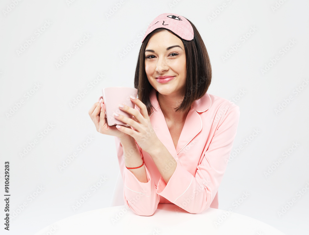 young brunette woman wearing pink pajama holding a glass of milk young brunette woman wearing pink pajama holding a glass of milk
