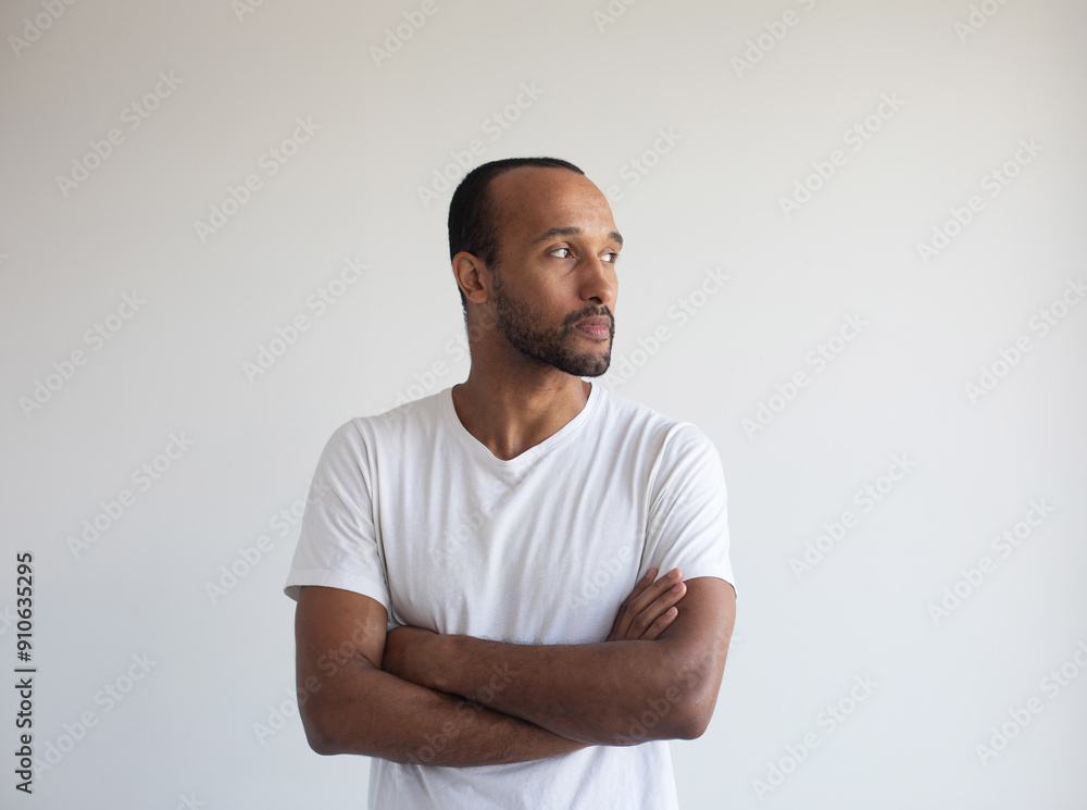 Portrait of young afro american man standing with arms crossed against light grey background Portrait of young afro american man standing with arms crossed against light grey background
