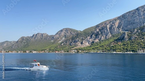 View of Ören holiday resort from a beach tour boat, highlighting impressive mountain range and small motor yacht underway calm waters. Tranquil scene captures beauty of nature. Milas, Turkey
 photo