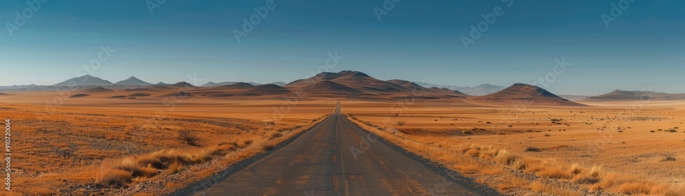 Panoramic View of a Long Desert Road Leading to Distant Mountains Under a Clear Blue Sky Panoramic View of a Long Desert Road Leading to Distant Mountains Under a Clear Blue Sky
