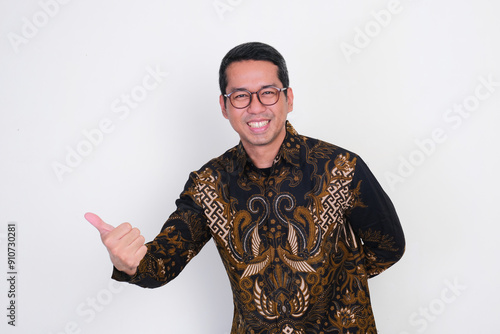 Adult Asian man smiling friendly at the camera while doing welcoming gesture photo